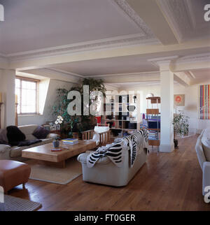 Faux zebra skin rug on white sofa in living area of a nineties loft conversion apartment with wooden flooring Stock Photo