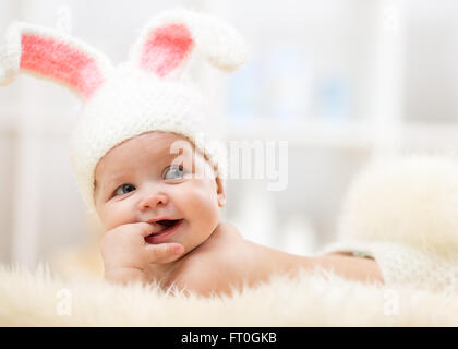 Cute baby lying on fur blanket and wearing a hat in the form of a Christmas bunny with pink ears Stock Photo