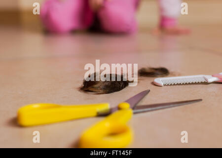 Selective focus on hair and cutting shears with baby blurry on background. Stock Photo