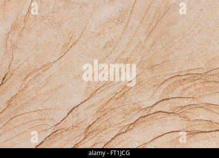 Abstract texture of a beige and brown stone slab with fine, curved lines in a rough surface. Taken in close-up. Stock Photo