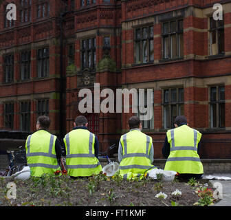 Four construction workers in high visibility clothing sitting on the streets of York during a break in work. Stock Photo