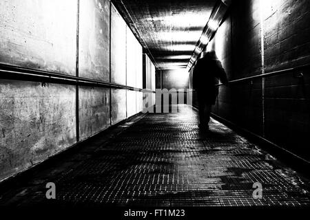 man walking alone in a tunnel Stock Photo