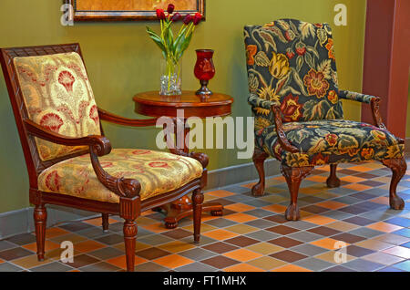Floral upholstered chairs on tile floor in formal entryway. Stock Photo
