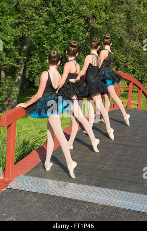 Four ballerinas on a bridge in the park practicing a routine Stock Photo