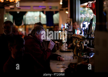 Middle aged man drinking a pint of beer alone in a pub Stock Photo