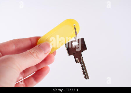 Hand holding metal key hanging on a yellow keyring Stock Photo