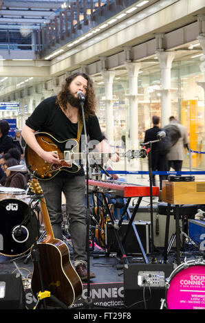 John Joseph Brill performing a 30 minute set at a  pop-up concert in St Pancras International Railway Station. Stock Photo