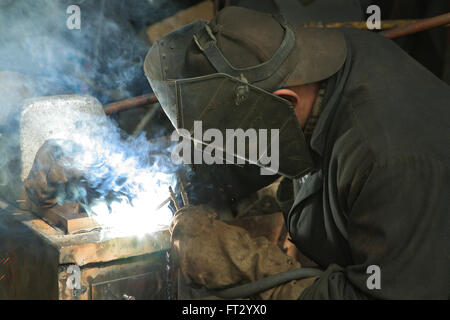 The worker is engaged in welding on a metal works Stock Photo