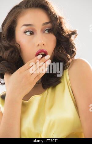 Beautiful young woman head and shoulders portrait in vintage yellow dress, with a shocked look. Stock Photo