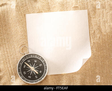 Blank sheet of paper with compass on sand Stock Photo