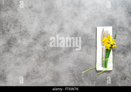 Fork, knife and napkin on table plate with spring flowers decoration Stock Photo