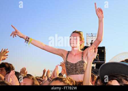 BENICASSIM, SPAIN - JULY 19: Young woman from the crowd with her arms raised in a concert at FIB. Stock Photo