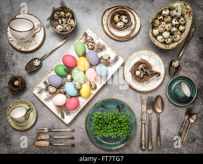 Table place setting with colored easter eggs. Vintage style dark toned picture Stock Photo