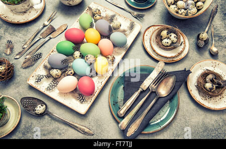 Table place setting decoration with colorful eggs. Easter dinner. Vintage style toned picture Stock Photo