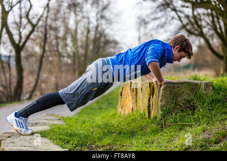 Young man is doing outdoor sports, fitness training, pushups, push ups, Stock Photo