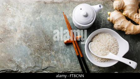 Raw white rice, soy sauce and sushi chopsticks on gray stone slate background Stock Photo