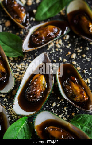 Asian dish - mussels in sticky sweet saucem with peanuts, on slate board Stock Photo