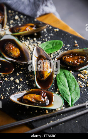 Asian dish - mussels in sticky sweet sauce, with peanuts and spinach Stock Photo