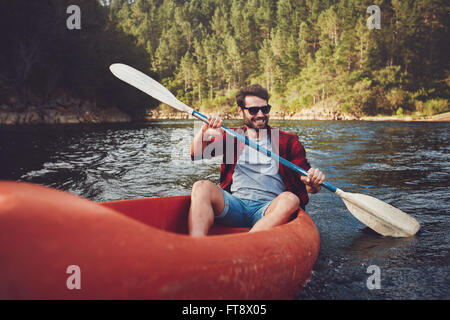 Young man kayaking on a lake. Happy young man canoeing in a lake. Stock Photo