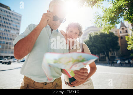 Senior couple looking at city map. Mature man and woman outdoors in city reading a map for direction. Stock Photo