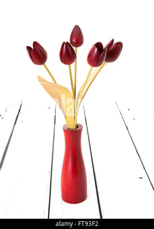 Five Red Tulips in a Wooden vase on a White Wooden Background Stock Photo