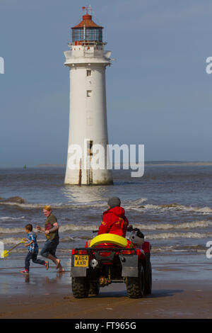 RNLI Lifeguards patrol the New Brighton beach using a Honda TRX 500 FM (Quad Bike), Wallasey, UK Holidaymakers enjoying the spring sunshine on the beach in front of Fort Perch Lighthouse. Britain is growing increasingly fond of so-called staycations, with travellers becoming more willing to take a short trip on these shores instead of venturing abroad. Events in Europe may now affect those British people who have their holidays in July and August, the most popular months for holidays. Stock Photo