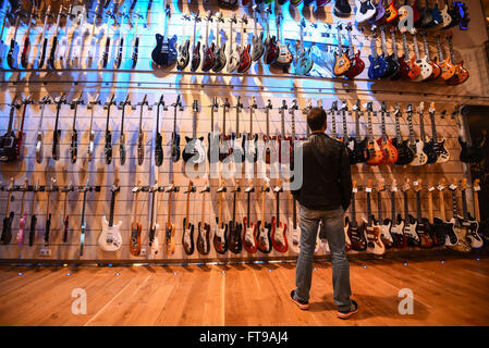 Treppendorf, Germany. 24th Mar, 2016. A customer stands in front of a wall of guitars in the Musikhaus Thomann in Treppendorf, Germany, 24 March 2016. The Musikhaus Thomann has become one of the world's largest online retailers in the music merchandise. The family-owned business is now defying the online giant Amazon. Photo: NICOLAS ARMER/dpa/Ģ����ý Live News Stock Photo