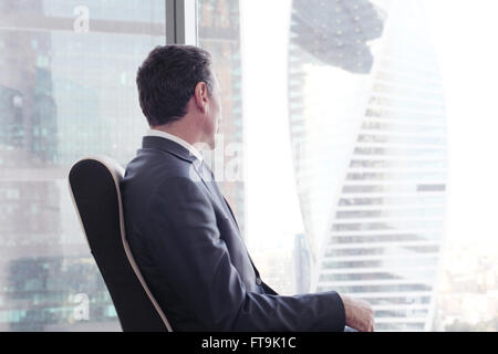 Portrait of a business man sitting on armchair against the window Stock Photo
