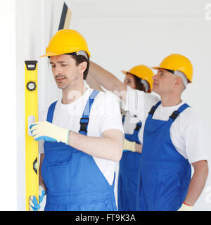 Building teamwork concept - group of smiling builders in hardhats with tools indoors Stock Photo