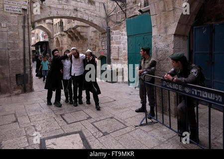 Members of the Israeli Security Forces stand guard as Orthodox Jews pass by in Al Wad street which Israelis call Haggai in the Muslim Quarter, old city of Jerusalem Israel Stock Photo
