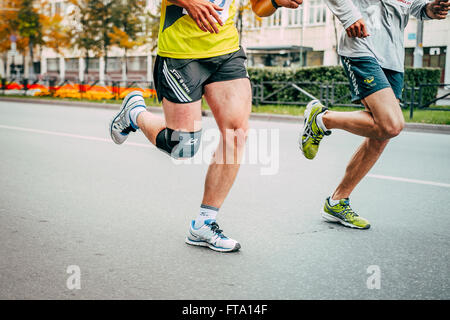 two male runners running through streets of city, only visible feet Stock Photo