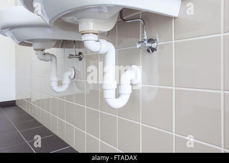 in an public restroom hangs on an wall of an white sink Stock Photo