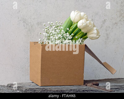 Beautiful spring flowers. Shabby chic in cardboard box on rustic dresser. Stock Photo
