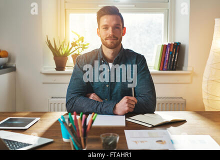 Confident authoritative young businessman working from a home office sitting looking at the camera with a thoughtful proud expre Stock Photo