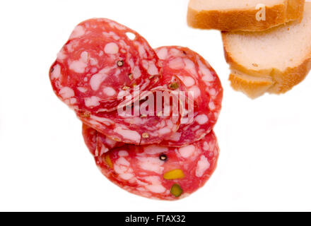 Slices of salami with pistachios on white background Stock Photo