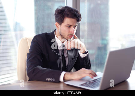 Busy businessman in office working on his laptop. Stock Photo