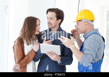 Worker and couple using tablet pc at construction site Stock Photo