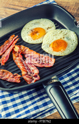 Ham and Egg. Bacon and Egg. Salted egg and sprinkled with black pepper. English breakfast. Grilled bacon, two eggs in pan Stock Photo