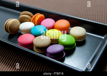 colorful macaroons in black ceramic plate on brown paper Stock Photo