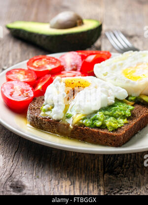 Open toast with avocado and egg, cherry tomatoes on a wooden background Stock Photo