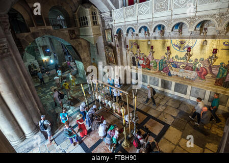 Pilgrims praying next to Stone of Anointing in Church of Holy Sepulchre, Jerusalem and mosaic depicts anointing of Jesus body Stock Photo