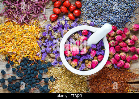Mortar of healing herbs, herbal tea assortment and berries on table. Top view. Herbal medicine. Stock Photo