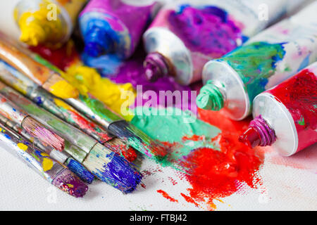 Tubes of multicolor oil paint and artist paintbrushes on canvas closeup. Stock Photo