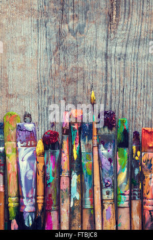Row of artist paint brushes closeup on old rustic wooden background. Stock Photo