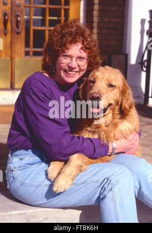Outdoor portrait of middle-aged woman with her Golden Retriever dog Stock Photo