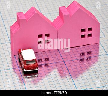 Two pink houses with a car parked in front on a blue squared shiny surface Stock Photo