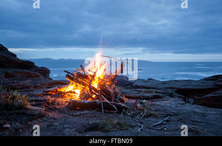 Beach Fire at Sunset, Juan de Fuca Strait, Vancouver Island, British Columbia Stock Photo