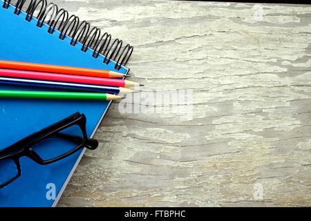 colored pencils, notebook and eyeglasses on a table Stock Photo