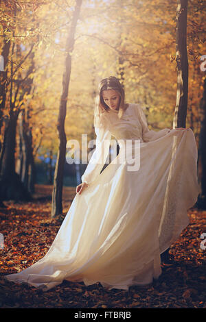 Beautiful woman with victorian dress in autumn woods . Sunset light