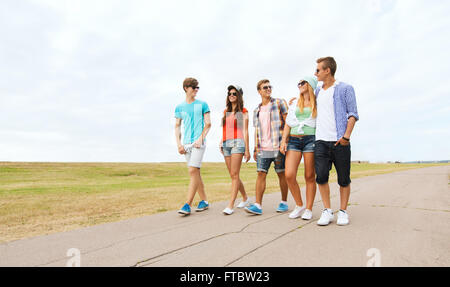 group of smiling friends walking on road Stock Photo